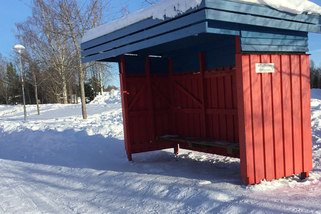 Foto på en röd busskur i ett snölandskap.
